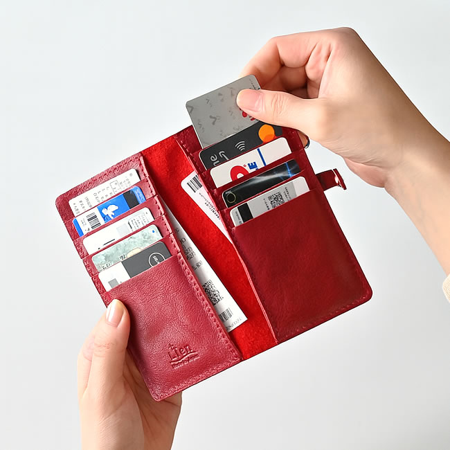  
レッドのカードケースを開きカードを収納している様子 