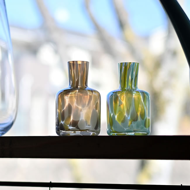 窓辺に並ぶ琥珀色とグリーンのガラスベース