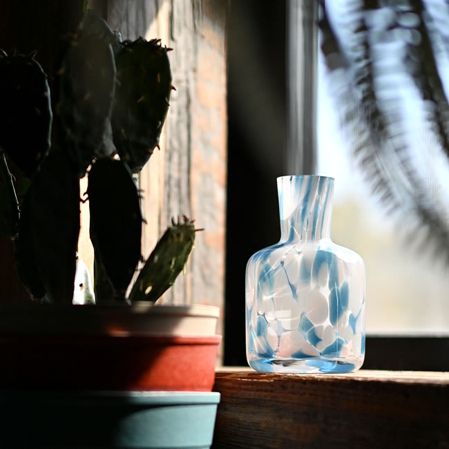 ブルーのマーブルガラスベースと植物のある窓辺