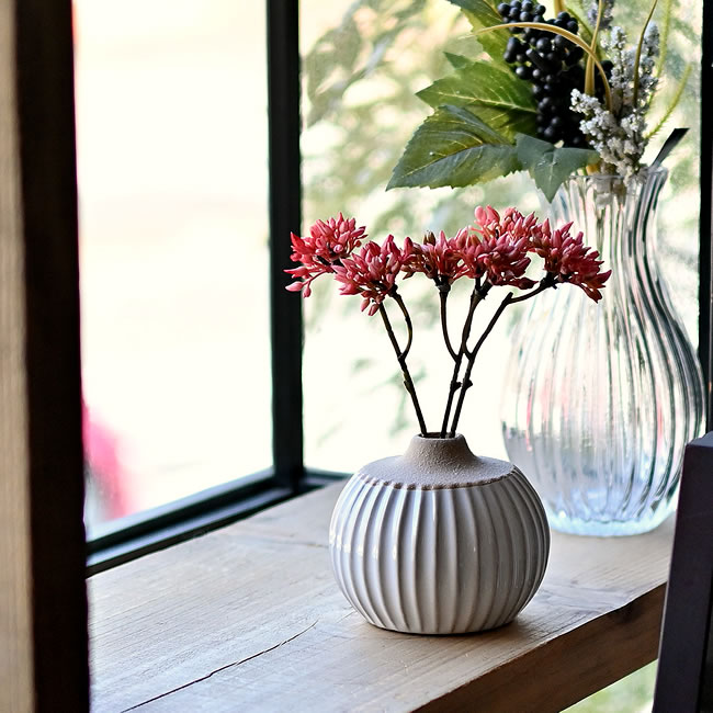 窓辺に置かれた白陶の一輪ベースと草花