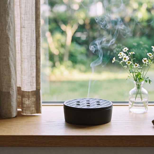 窓辺に置いた信楽焼の蚊遣り器から蚊取り線香の煙が立ち上る様子