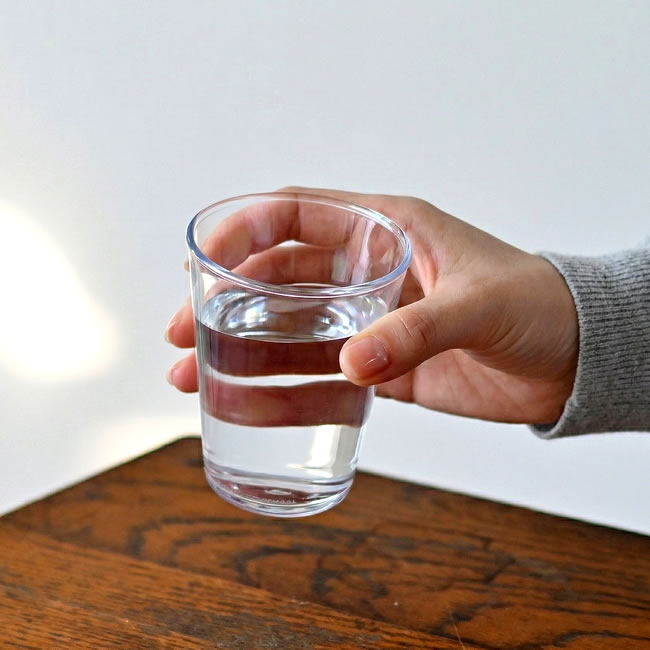 手に持った透明な壊れないグラス