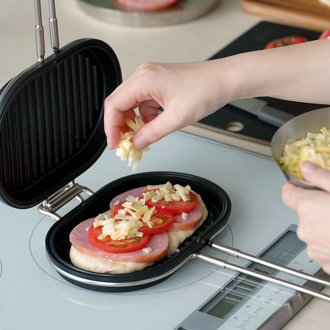 パニーニパンにパンやハムやトマトやチーズをのせている調理風景