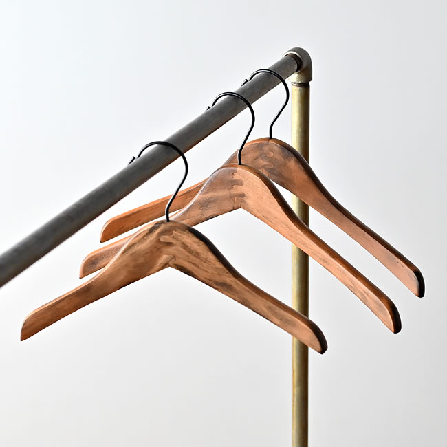  
3本の天然木製ウッドハンガーがアイアンバーに掛けられている様子。シンプルで温かみのあるデザイン。 