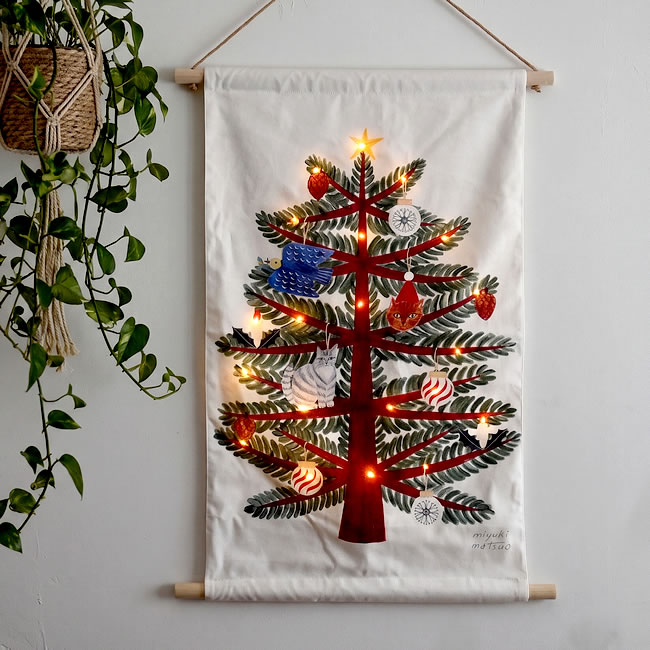 LEDが灯るクリスマスツリー柄のタペストリーを壁に飾った様子