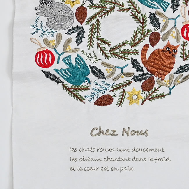 猫や鳥、植物の刺繍と、リースの下に綴られたフランス語の拡大